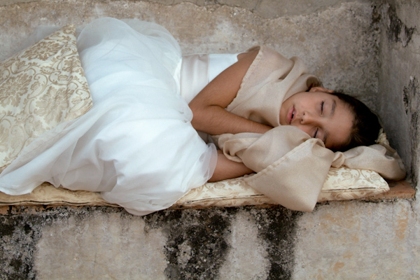 adorable photo of a sleeping flower girl in a white dress lying on gold cushions and pillows - photo by Italian wedding photographer JoAnne Dunn